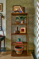 Showroom corner featuring green textured hemp wallpaper and shelving displaying accessories from Lauren Elliot’s curated collection at Christopher Farr Cloth.